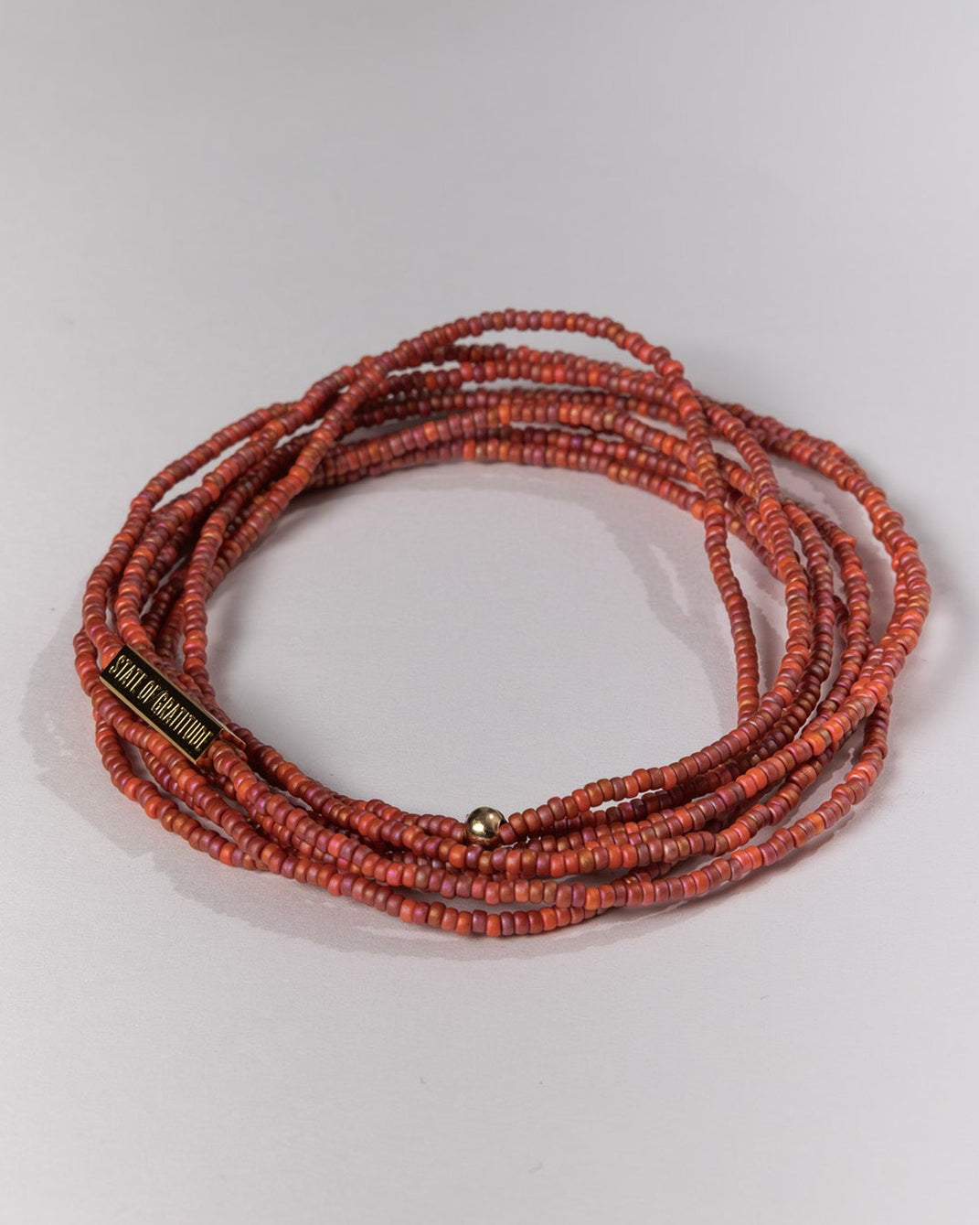 Stack of red beaded bracelets on a light gray background