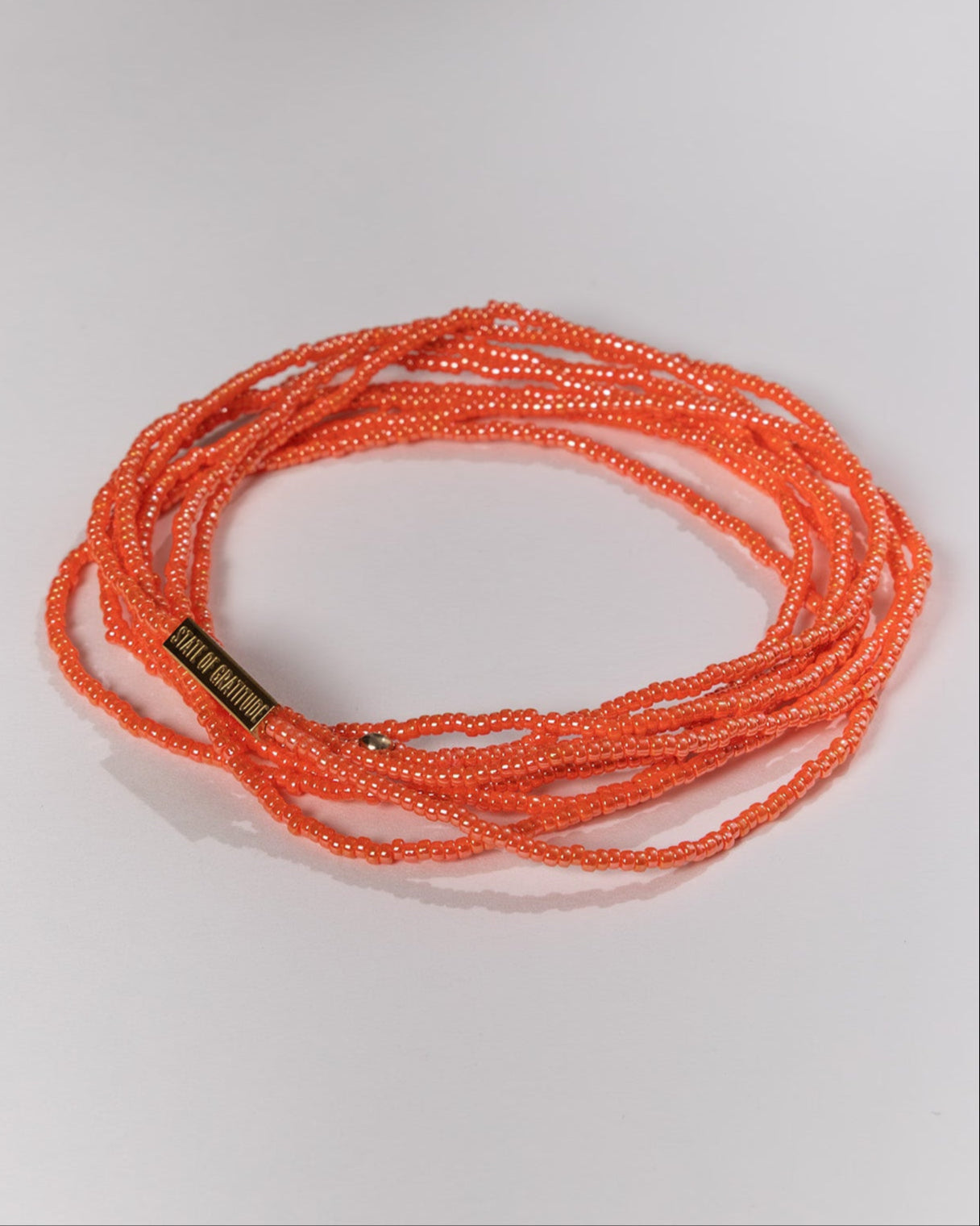 Orange beaded necklace on a light gray background