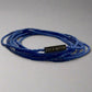 Blue beaded bracelet with a black tag on a gray background