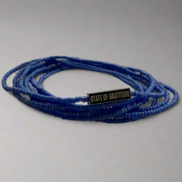 Blue beaded bracelet with a black tag on a gray background
