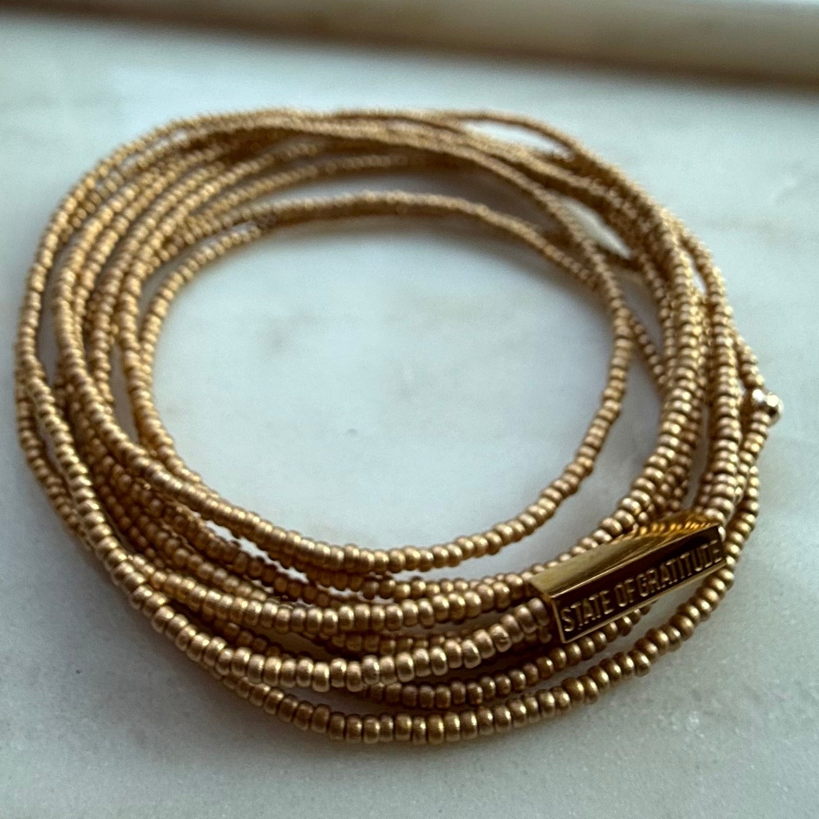 Gold bracelets on a marble surface with a blurred background