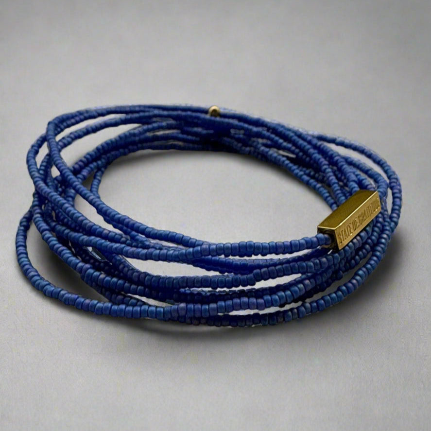 Blue beaded bracelet with a gold clasp on a gray background