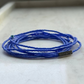 Blue beaded necklace with a metal tag on a light gray background