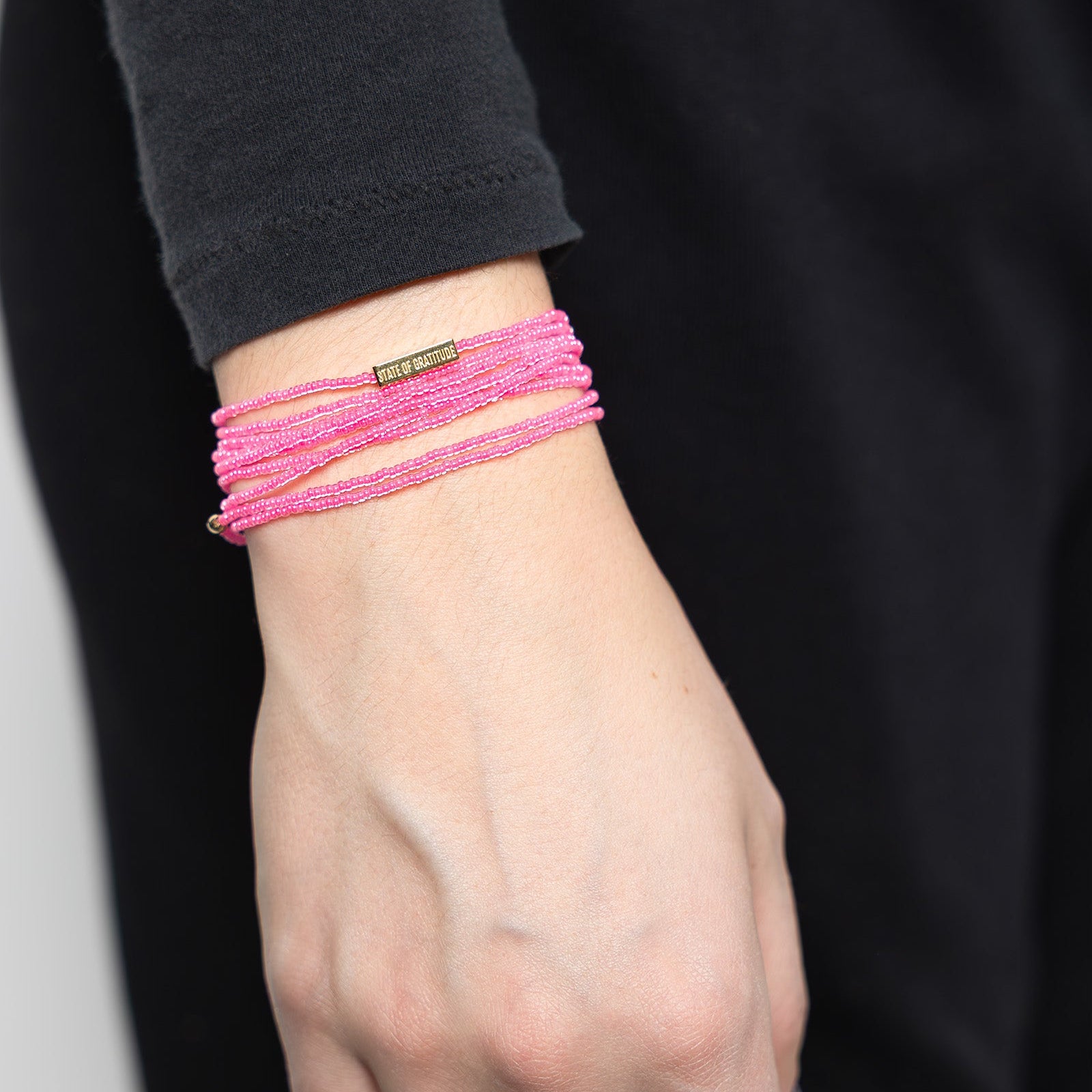 Hand wearing pink bracelets with a blurred background