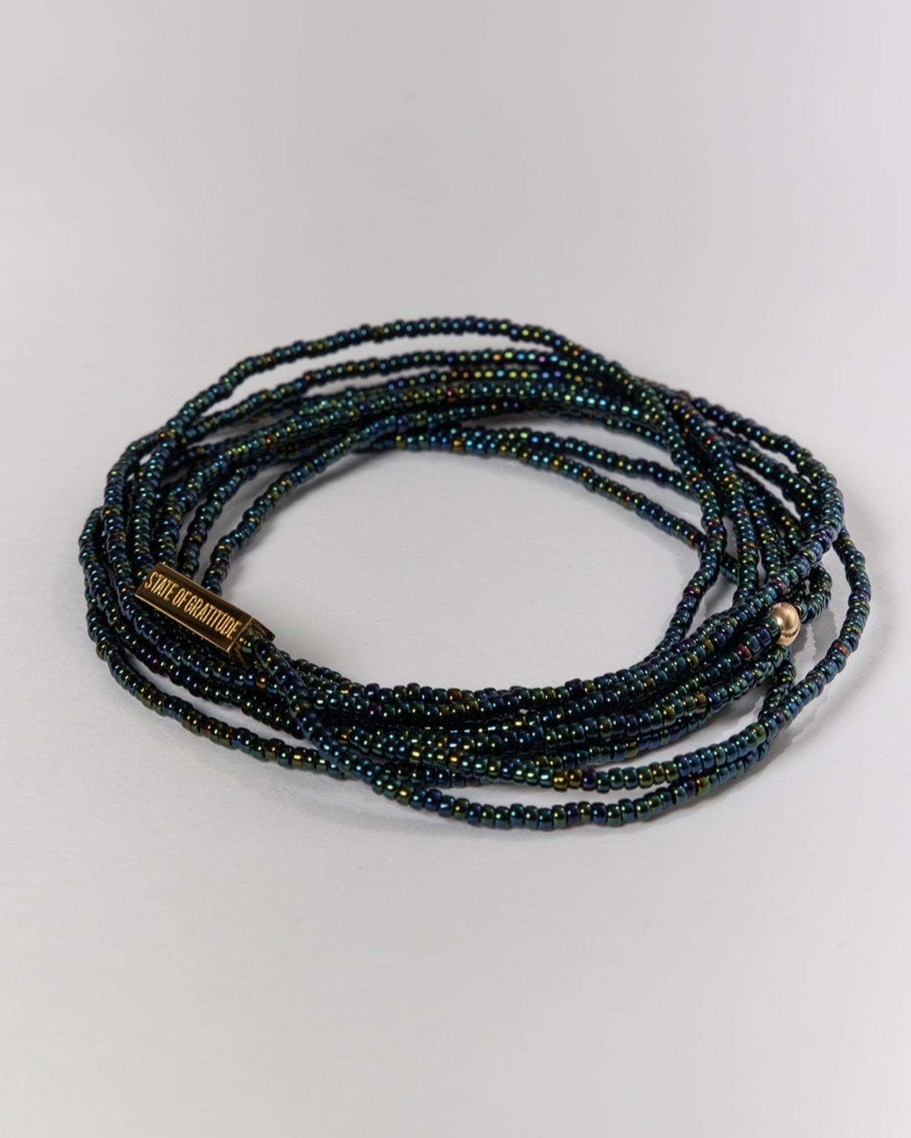 Multistrand beaded bracelet with a brand tag on a light gray background