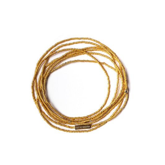 Gold beaded bracelets stacked on a white background