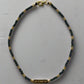 single-stranded bracelet with gold and dark blue beads on a light gray background