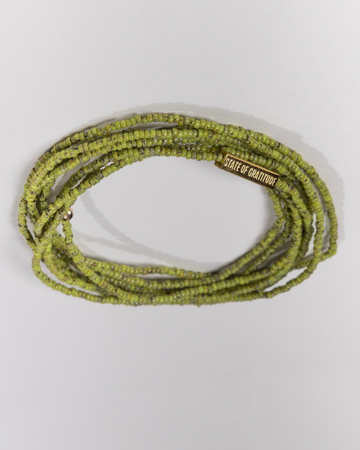 Green beaded bracelet with a brand label on a white background