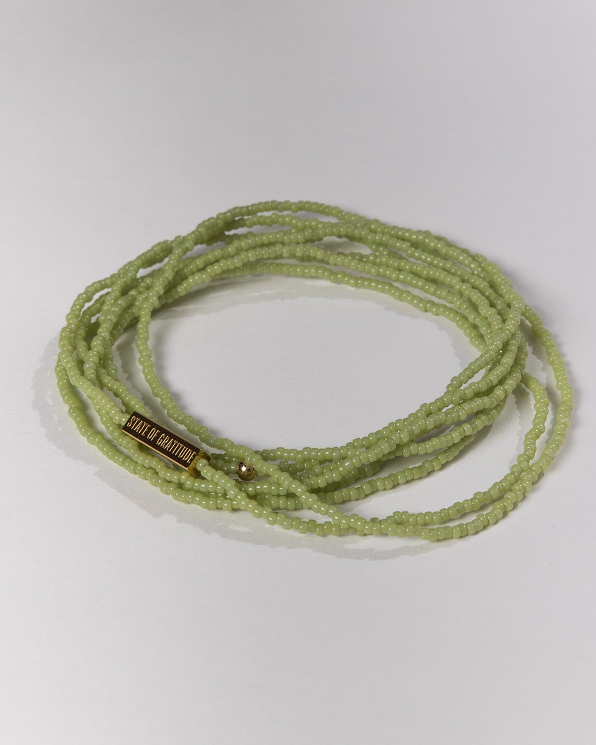 Green beaded bracelet on a light gray background