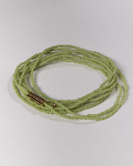 Green beaded bracelet on a light gray background