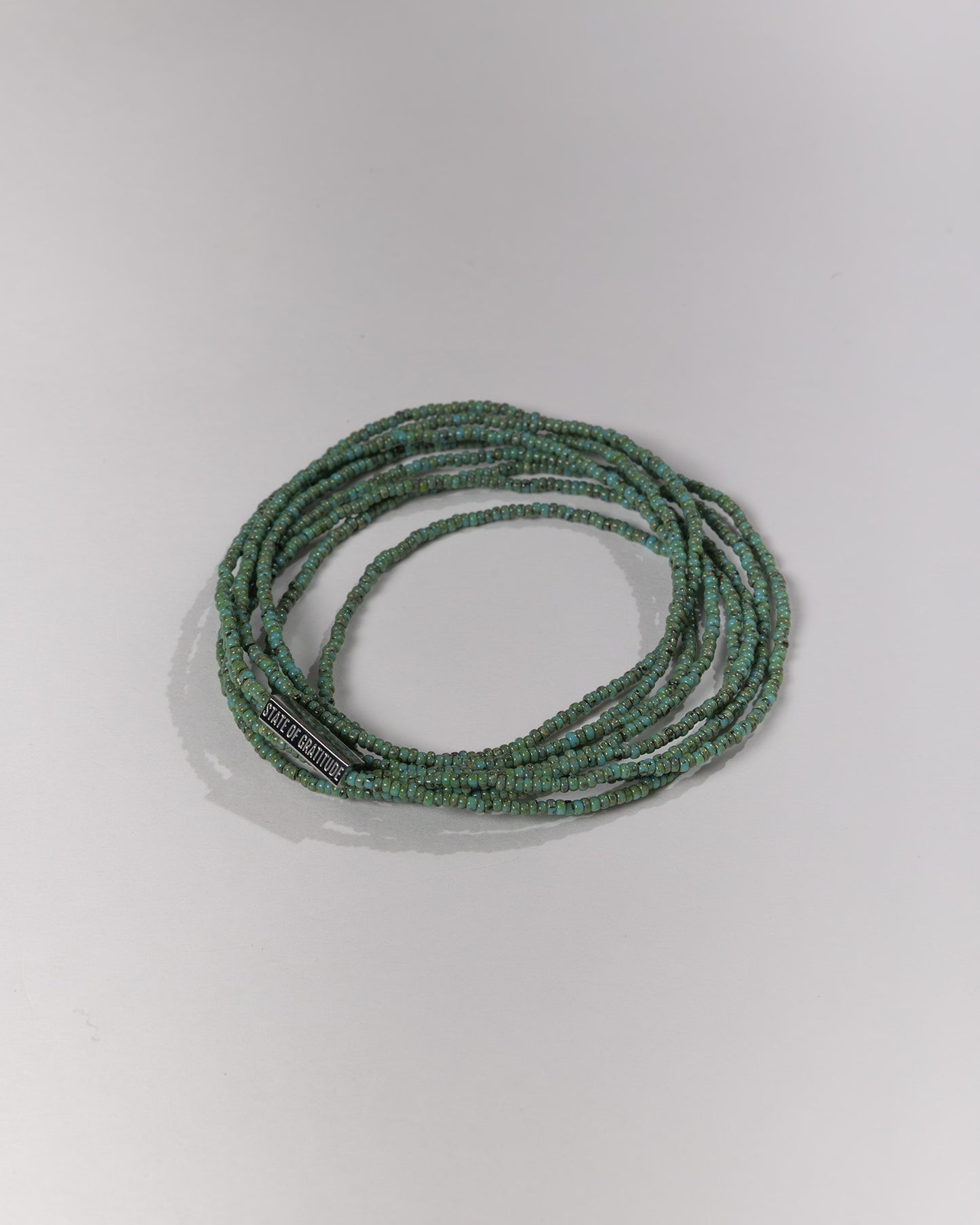 Green beaded bracelet on a light gray background