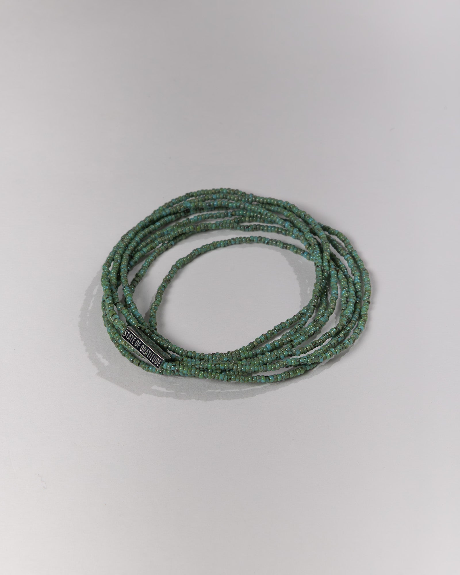 Green beaded bracelet on a light gray background